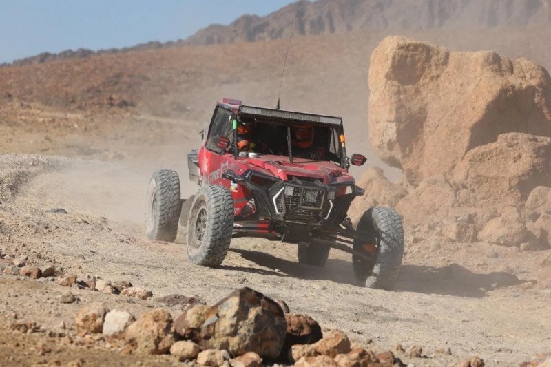 Jim Beaver vehicle in desert driving by large rock