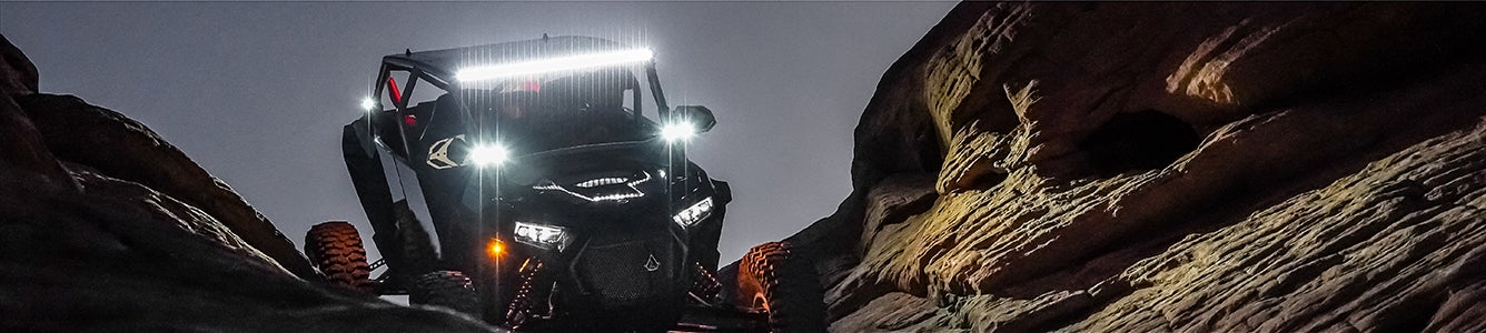 UTV driving through rocks at night with illuminated RIGID lights